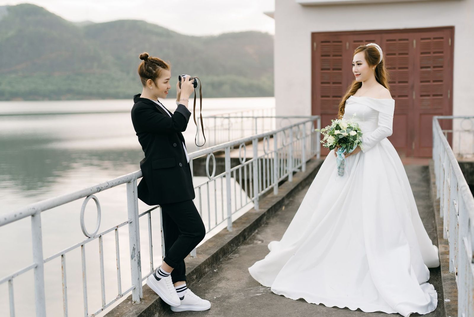 Braut im Kleid posiert am See und wird fotografiert