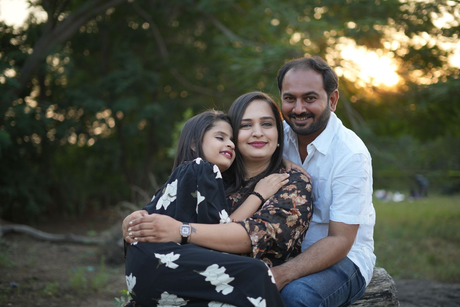 Familie zu dritt umarmt sich im Freien bei Abendsonne
